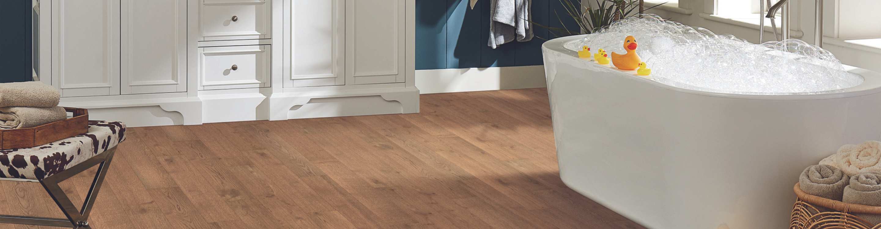 engineered hardwood planks in bathroom with blue wall and bubble bath